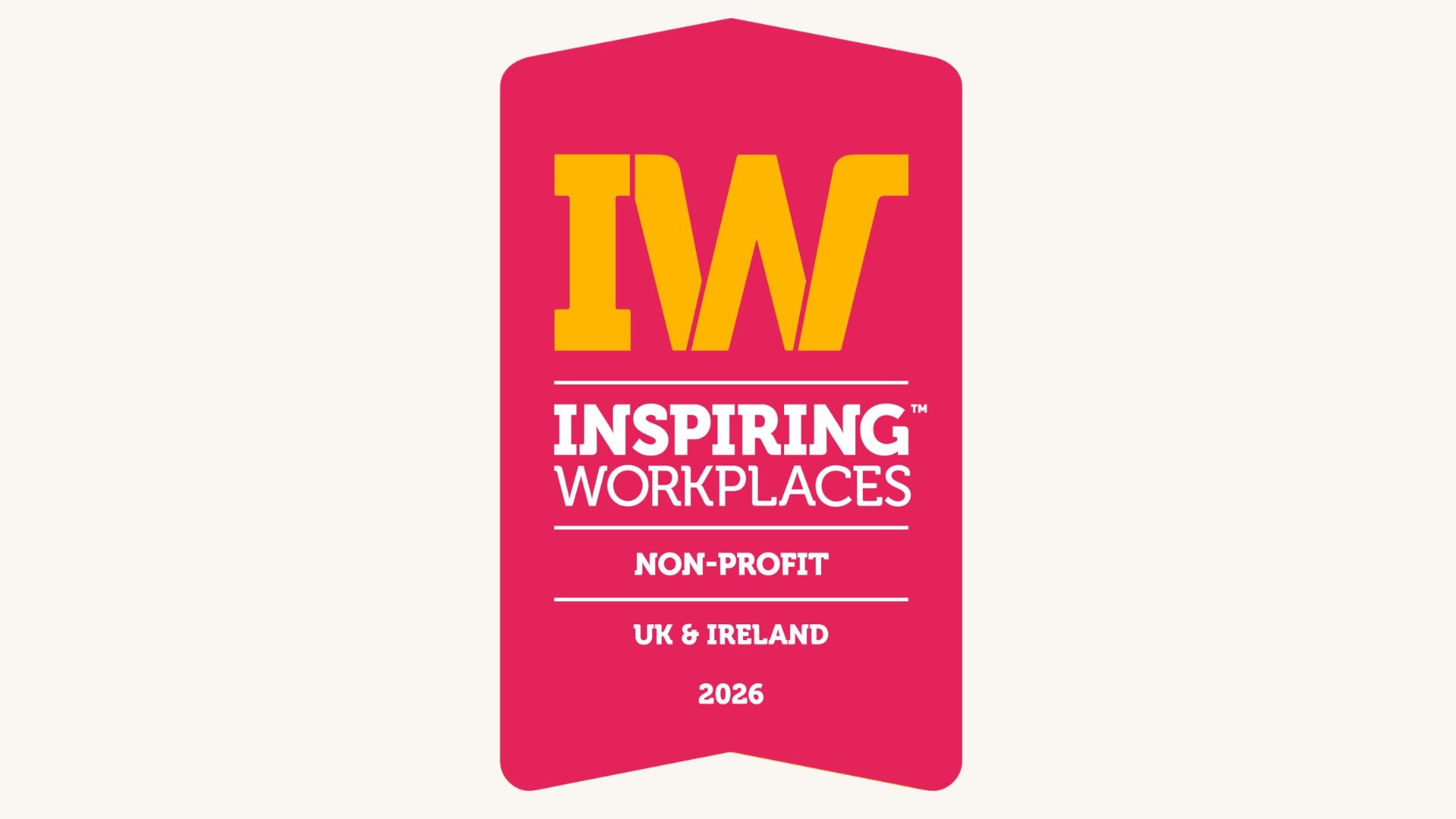 Pink award badge with large yellow “IW” initials and white text reading “Inspiring Workplaces Non-Profit, UK & Ireland 2026.”